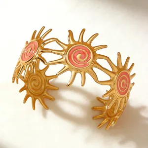 Detail of gold sunburst cuff bracelet featuring pink enamel and spiral texture
