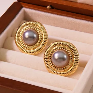 Nahaufnahme von Vintage-Knopfohrringen in Gold mit Flieder-Perlen auf Samt