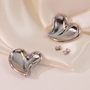 Polished silver heart earrings set on elegant white silk fabric with butterfly backings