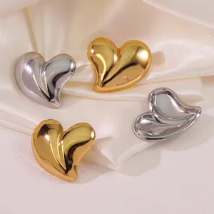 Detailed close-up of metallic heart earrings in gold and silver with mirror finish