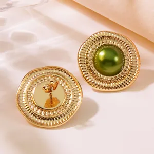Detail von Vintage-Goldohrringen mit grüner Perle und plissierter Metallstruktur