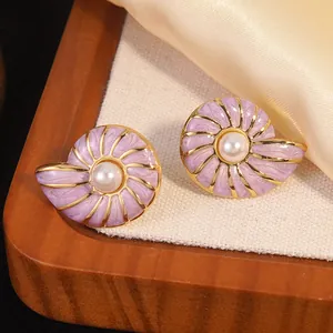 Detailed shot of purple enamel snail shell earrings with pearl inlay on silk and wood