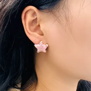 Gros plan détaillé des boucles d'oreilles étoile rose et spirale dorée sur l'oreille