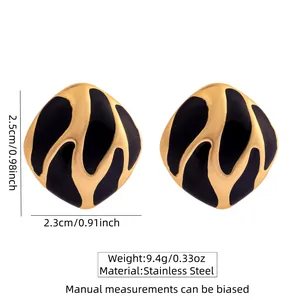 Détail de boucles d'oreilles en acier inoxydable avec émail noir et texture dorée ondulée