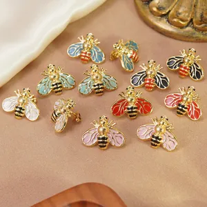 Gros plan sur des boucles d'oreilles abeille en émail coloré et acier doré poli
