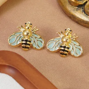 Détail des boucles d'oreilles abeille avec ailes en émail menthe et finition dorée