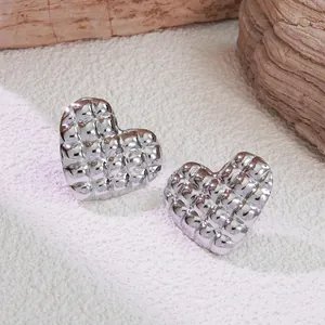 Macro shot of silver heart-shaped stud earrings with quilted pattern and mirrored finish