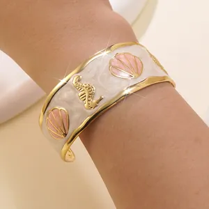 Dettaglio di un bracciale a C placcato in oro con smalto bianco e motivo a cavalluccio