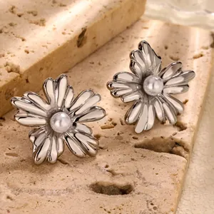 Orecchini a fiore in acciaio inossidabile con perla centrale su sfondo di pietra naturale