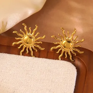 Close-up of golden sunburst stud earrings displayed on a white textured stand
