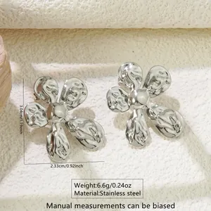 Detail of silver stainless steel flower earrings with liquid metal texture on stone surface