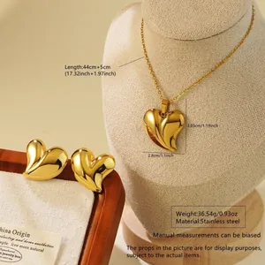 Détail d'un ensemble de bijoux cœur en acier inoxydable doré sur un support en bois