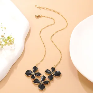 Detail von drei schwarzen Emaille-Blumenanhängern an einer vergoldeten Gliederkette