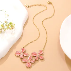 Detail einer eleganten Goldkette mit drei rosa Emaille-Blumen und verstellbarer Kette