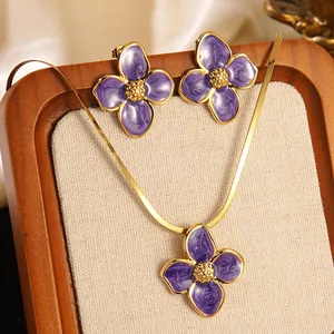 Dettaglio parure gioielli fiori viola smaltati con catena a serpente dorata
