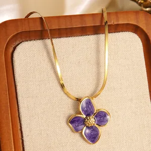 Dettaglio catena serpente dorata con pendente a fiore in smalto viola su vassoio gioielli