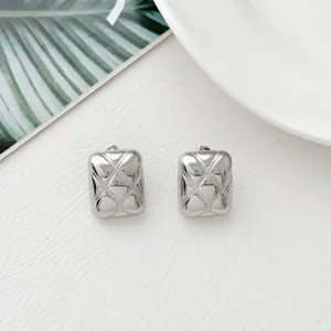 Macro detail of silver rectangular stud earrings with classic quilted texture design