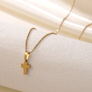 Détail du pendentif croix plaqué or 18k avec une élégante texture gaufrée à pois