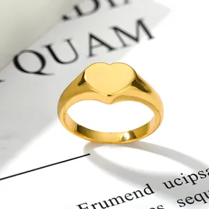 Detailed close-up of a polished gold heart signet ring on minimalist paper background