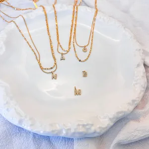 Dettaglio della collana a strati in acciaio dorato con ciondoli a lettere in strass
