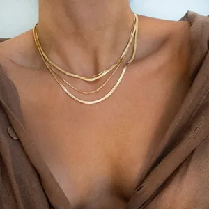 Close-up of triple-layered gold necklaces with box, snake and flat snake chain textures
