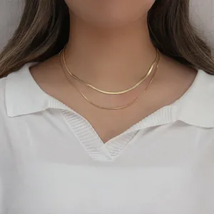 Detail of layered gold stainless steel snake and box chains on a model neck