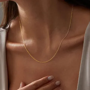 Close-up of 14K gold plated stainless steel thin chain necklace on a model's collarbone