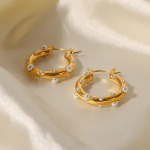 Dettaglio di orecchini a cerchio placcati oro 18K con perle su seta elegante