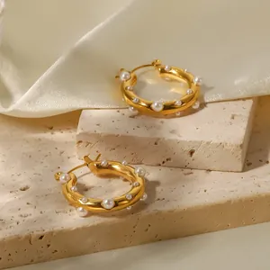 Eleganti orecchini a cerchio placcati oro 18 carati con perle bianche su sfondo di pietra