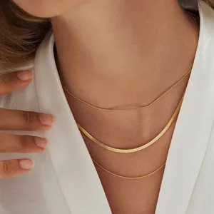 Close-up of triple-layered gold snake chains on a female model neck featuring metallic luster