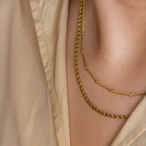 Close-up of layered gold double strand necklace with twisted rope and bead chain design
