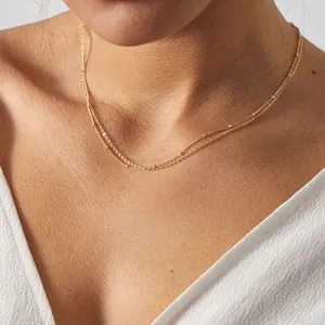 Close-up of double-layered gold necklace with delicate bead details on a female model