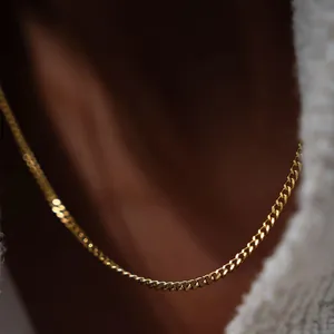 Minimalistische vergoldete Panzerkette für Damen auf weißem Pullover getragen