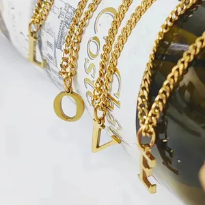 Gold 14K stainless steel necklaces with LOVE letter pendants on white wine bottle