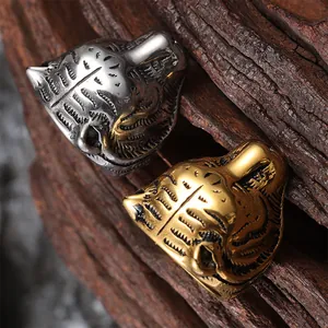 Detailed close-up of tiger head rings in silver and gold steel over a wood background