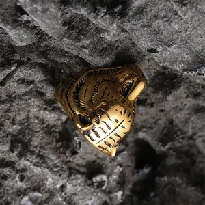 Detail of masculine gold tiger head ring with black accents on a dark stone background