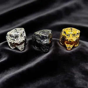 Detailed view of three tiger head rings in silver, black and gold on grey velvet