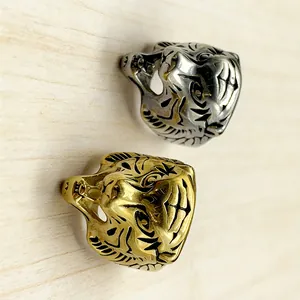 Detailed close-up of tiger head rings in gold and silver finishes on a wooden surface