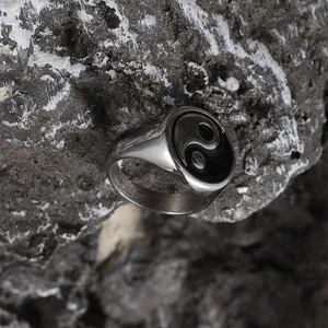 Macro detail of retro stainless steel ring with Yin Yang Tai Chi symbol on volcanic rock