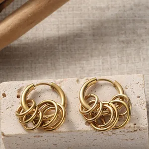 Gold titanium steel hoop earrings with layered small rings on a textured stone base