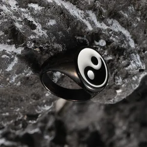 Macro shot of stainless steel Yin Yang ring with black and white enamel on a rock