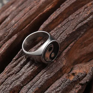 Macro close-up of vintage stainless steel Tai Chi Yin Yang ring on a rustic wood background