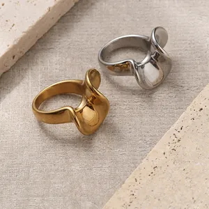 Minimalist 18K gold and silver irregular wave rings set on natural stone background