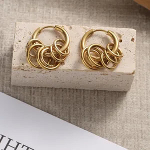 Polished gold multi-layered hoop earrings with cascading rings on a stone display base