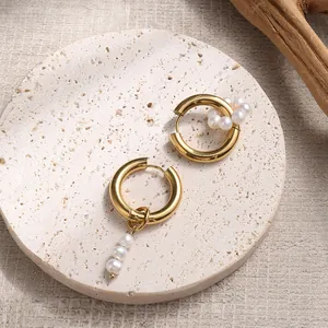Elegant asymmetric gold hoop earrings with freshwater pearls on a stone tray