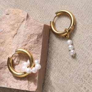 Asymmetric gold hoop earrings with natural freshwater pearls on a textured rock base