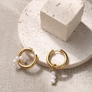 Detail view of asymmetric gold hoop earrings with white pearls on elegant stone display