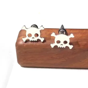 Gros plan de boucles d'oreilles tête de mort en acier inoxydable sur bois