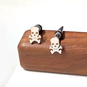 Boucles d'oreilles tête de mort en acier inoxydable poli sur support en bois
