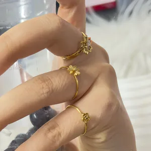 Vue détaillée de trois bagues dorées à fleurs avec motifs de rose et marguerite et zircons